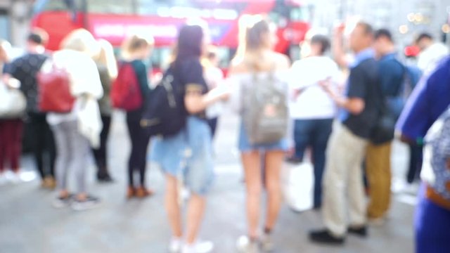 Cinematic time-lapse defocused silhouettes of pedestrians people walking in slow motion on Oxford Circus interchange between the Bakerloo, Central and Victoria lines waiting to cross the street