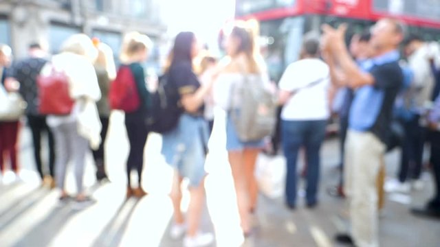Cinematic slow motion defocused silhouettes of pedestrians people walking in  on Oxford Circus interchange between the Bakerloo, Central and Victoria lines double-decker bus driving in front