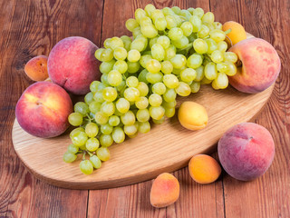 Different fruits on the oval wooden serving board and beside