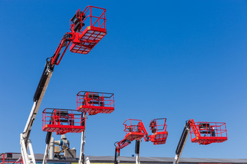Red baskets on the booms of articulated boom lifts