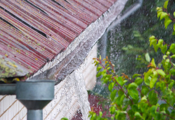 Water overflowing from damaged rain gutter during heavy rainstorm