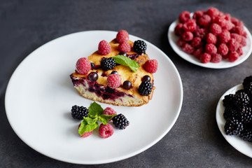 Piece of pie with blueberries, rasberry and mint for dessert on a white plate, napkin. Pieces of delicious homemade cake on a background