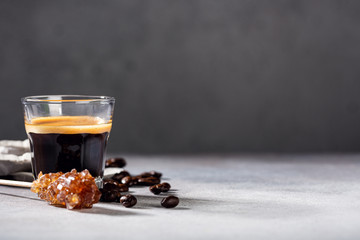 Coffee freshly brewed in a glass cup with beans and leafs. Food background with copy space.