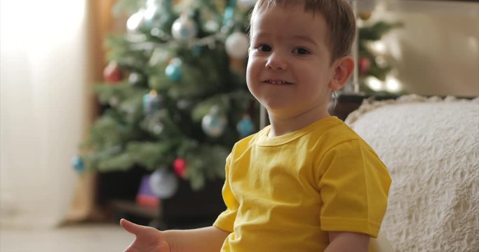Funny little boy smiling on the background of Christmas lights, cute baby looking at the camera, smiling, happy. Happy child.