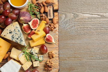 Set of different snacks with ripe figs served on wooden table, top view. Space for text
