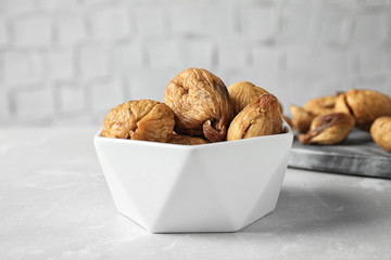 Bowl of tasty dried figs on light grey marble table, closeup