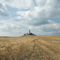 Fototapeta na wymiar cross on the hill and lighthouse
