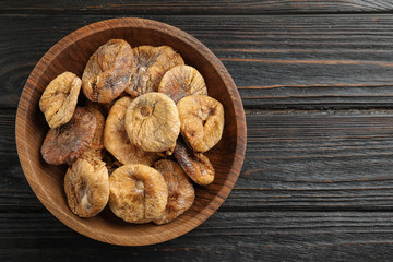 Wooden bowl of tasty dried figs on black table, top view. Space for text