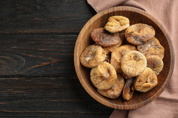 Wooden bowl of tasty dried figs on black table, top view. Space for text
