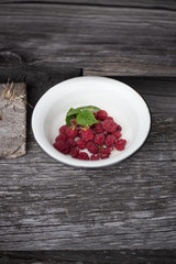Ripe raspberry with leaf in old retro plate