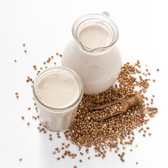Organic non-milk buckwheat drink in a glass jug and in a glass on a light background with copy space. Vegan healthy food concept. Selective focus.
