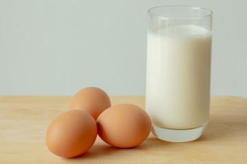 glass of milk and eggs  on the wooden table and gray background.