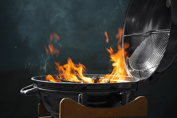 New modern barbecue grill with burning firewood on dark background
