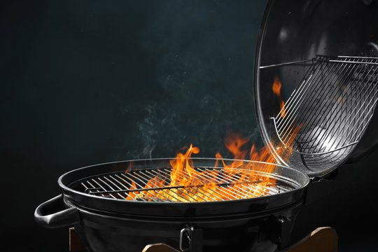 Modern barbecue grill with burning fire on dark background