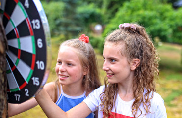 two young friends play darts outdoors