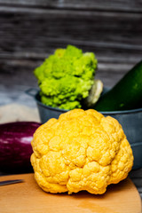 Chou-fleur jaune aubergine courgette chou romanesco sur une planche à découper, légumes bio du jardin