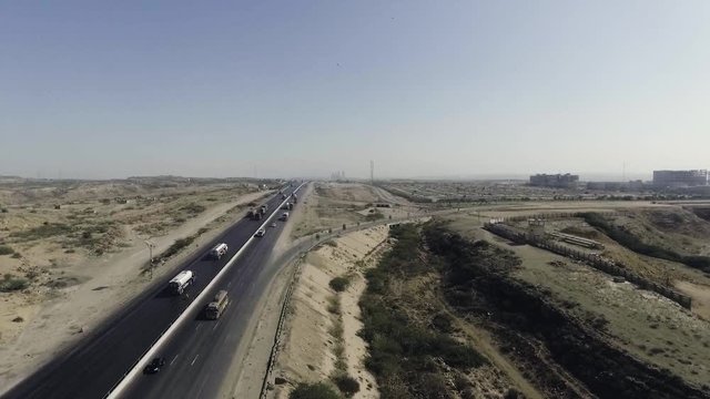An aerial slow mo view of a highway and city, The heavy trawlers and cars are moving on the highway, an interchange is connecting.