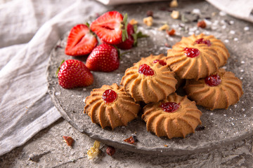 Obraz na płótnie Canvas Biscuit with strawberry filling. Crispy and crumbly delicious cookies with natural ingredients: flour, nuts, seeds, pieces of chocolate, cocoa, fruit jams. Spring Flower Still Life