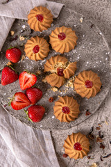 Fototapeta na wymiar Biscuit with strawberry filling. Crispy and crumbly delicious cookies with natural ingredients: flour, nuts, seeds, pieces of chocolate, cocoa, fruit jams. Spring Flower Still Life
