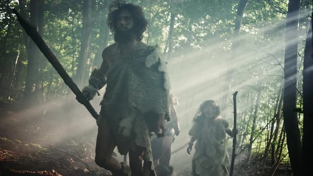 Tribe of Hunter-Gatherers Wearing Animal Skin Holding Stone Tipped Tools, Explore Prehistoric Forest in a Hunt for Animal Prey. Neanderthal Family Hunting in the Jungle or Migrating for Better Land