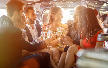 Group of women and men clinking glasses in a limousine