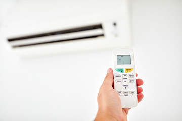 Modern air conditioner unit with a hand holding a remote.