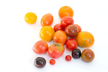 Naklejka na ściany i meble Multicolored tomatoes on a white background. Fresh harvest.