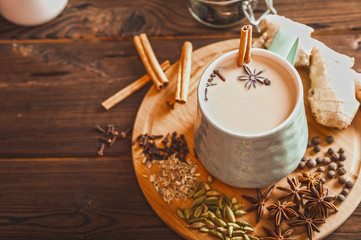 Details of still life in the home interior living room. Beautiful Cup of tea with milk, star anise, cinnamon on a wooden background. Cozy autumn-winter concept. Masala is a traditional hot spicy drink