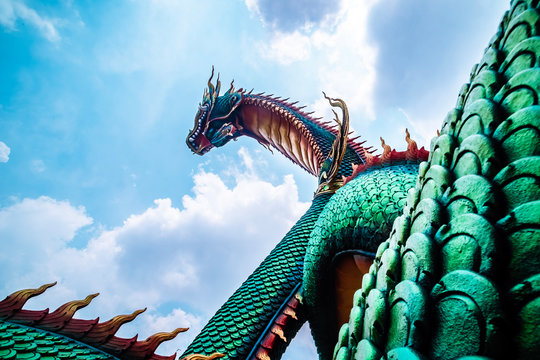 Beautiful green naga or serpent statue with blue sky and clouds background in thailand,