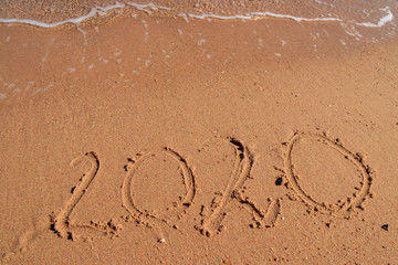 Concept of Christmas and New Year's holidays at tropical resort. 2020 number written on wet sand of sea beach