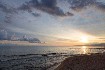 Beautiful sunset on a lake in the mountains. Kyrgyzstan, Issyk-Kul Lake. Bright sky, background in warm colors.