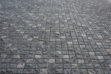 Fototapeta premium Gray square small stone brick paved pavement surface low angle close-up