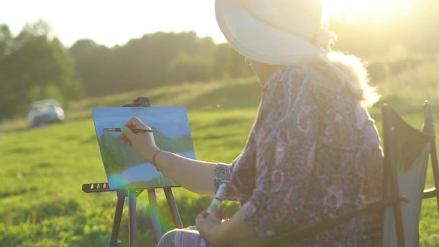 an elderly woman draws in nature