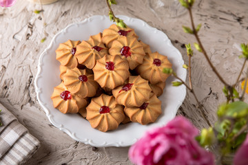 Biscuit with strawberry filling. Crispy and crumbly delicious cookies with natural ingredients: flour, nuts, seeds, pieces of chocolate, cocoa, fruit jams. Spring Flower Still Life