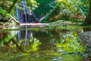 Waterfall surrounded by greenery. Acquacaduta. Friuli, Italy