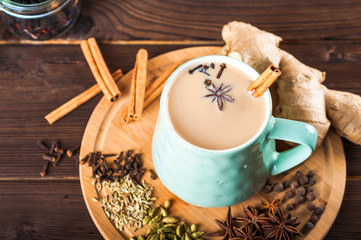 Details of still life in the home interior living room. Beautiful Cup of tea with milk, star anise, cinnamon on a wooden background. Cozy autumn-winter concept. Masala is a traditional hot spicy drink
