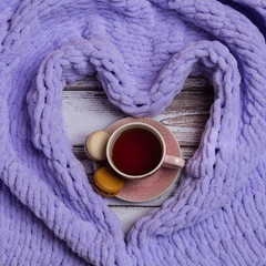 Cup of a tea with macaroons with plaid around.