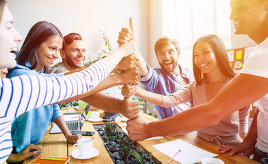 Group of happy, excited and successful modern people in office. Start up business team are holding hands together in circle. Company of young students are celebrating some win. 