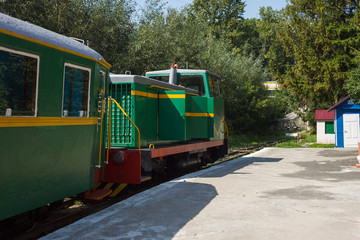 Fototapeta na wymiar Children's railway. Green train with wagons on the platform