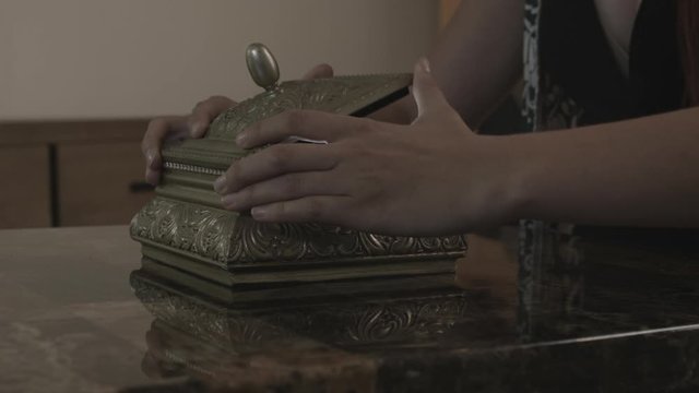 Woman's hands open an elegant box on a modern tabletop to reveal a glowing light inside