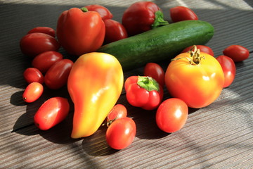  Fresh vegetables lie on a wooden table. Gifts of summer lit by the bright sun.