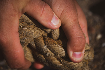 A mans hands holding worn old rope