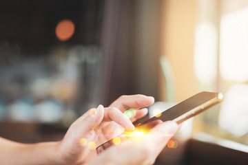 Woman hand using smart phone on old wood table texture background at coffee shop.