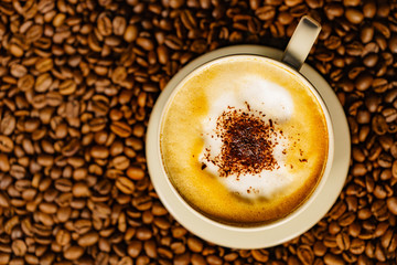 Cappuccino cup on roasted coffee beans.