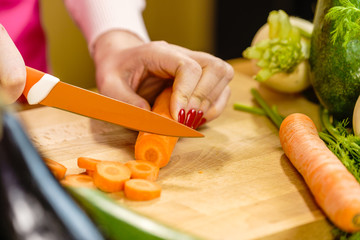 Woman cutting carrot on kitchen board