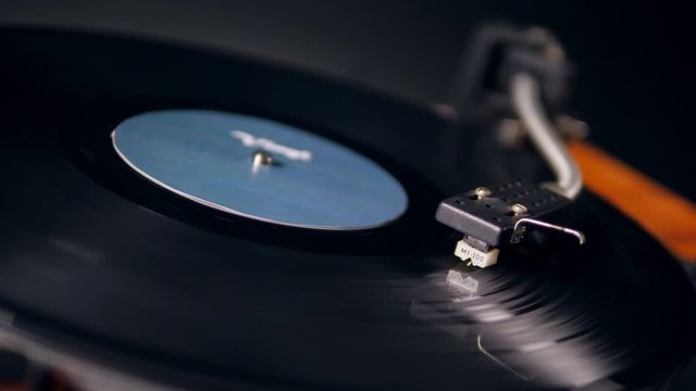 One person puts a metal needle of a vinyl player onto a record.