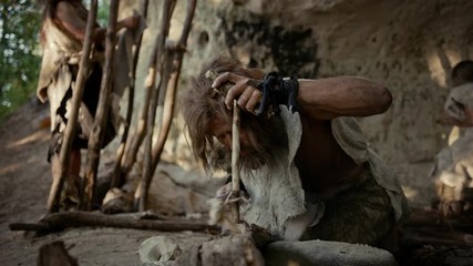 Primeval Caveman Wearing Animal Skin Trying to make a Fire with Bow Drill Method. Neanderthal Kindle First Man-Made fire in the Human Civilization History. Making Fire for Cooking. Slow Motion