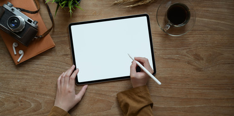 Top view of female hand writing on blank screen tablet on modern rustic table background