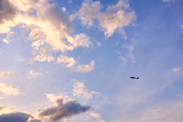 Tiny plane in front of a colorful and cloudy sky in vivid evening athmosphere
