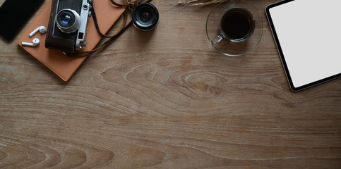 Overhead shot of rustic wooden workplace with blank screen tablet with vintage camera